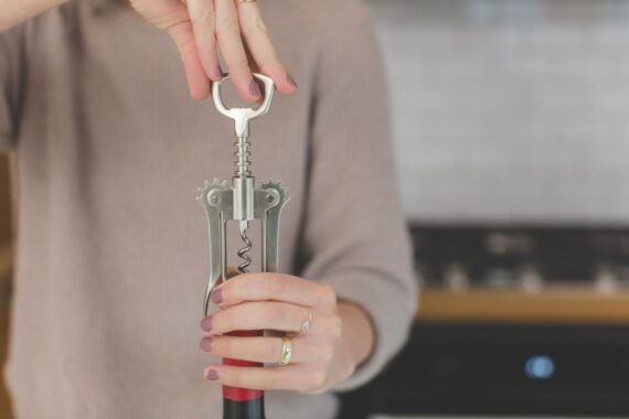 Main tenant un tire-bouchon bilame, prêt à ouvrir une bouteille