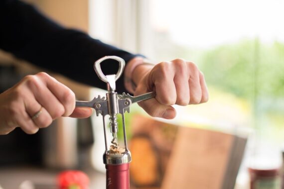 Mains utilisant un limonadier à double levier sur un bouchon de vin